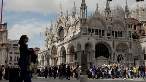 A-busy-day-in-front-of-the-Saint-Mark's-Basilica-Cathedral,-as-people-go-about-their-day-sightseeing-and-visiting-the-popular-historical-landmark-in-Venice,-Italy