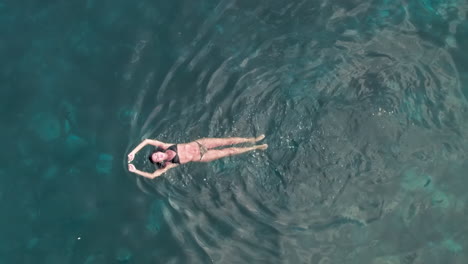 Aerial-birdseye-view-of-woman-swimming-in-the-sea