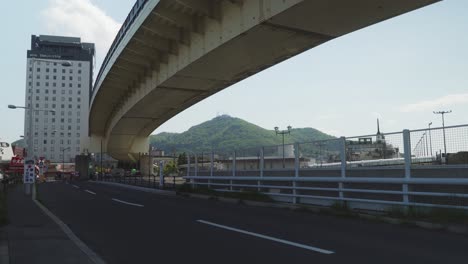 Empty-Road-With-Overpass-And-View-Of-Mount-Hakodate-In-Distant-Background