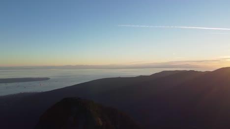 Bright-Sunset-Drone-Pan-Over-Mountain-Landscape-with-Ocean-and-Vancouver-City