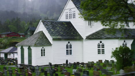 Slow-dolly-shot-past-a-church-and-a-cemetery-in-the-countryside-of-Vestlands,-Norway