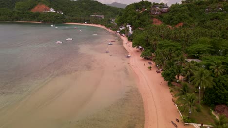 Wide-aerial-overview-of-outrigger-canoes-and-boats-on-sandy-shores-of-el-nido