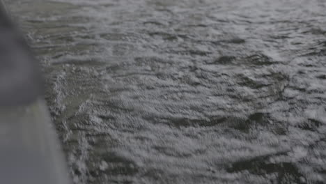 Water-passing-by-a-moving-boat-in-slowmotion-creating-small-waves-and-splashing-foamy-water-LOG