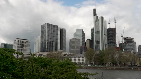 Frankfurt-Skyline-View-From-Across-River-Main-Over-Tree-Line-With-Light-Wind-Blowing