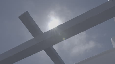 Low-angle-shot-of-a-wooden-ceiling-frame-in-front-of-a-blue-sky-with-the-sun-creating-flares-LOG