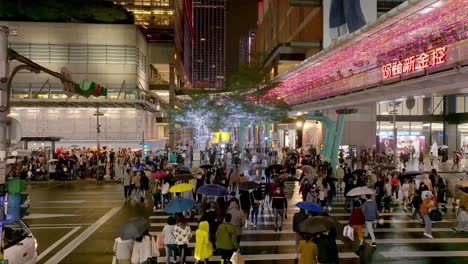 Aerial-view-of-Asian-people-with-umbrella-crossing-crosswalk-in-Taipei-City-at-night---Christmas-Season-with-decorated-buildings