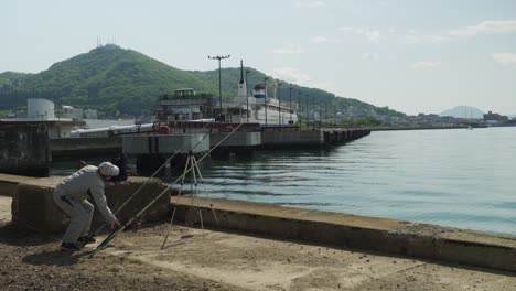 Lokale-Fischer-überprüfen-Seine-Angelrute,-Die-Neben-Dem-Pier-Im-Hafen-Von-Hakodate-Ruht