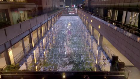 Aerial-backwards-flight-over-chain-of-lights-in-Shopping-center-during-Christmas-time-at-night---Taipei,-Taiwan