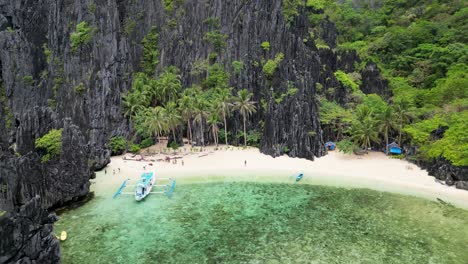Peaceful-sandy-beach-with-paraw-bangka-boat-and-sheer-rocky-palawan-cliffs