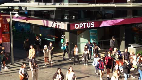 Tilt-down-view-of-the-Optus-flagship-store-along-Brisbane's-Queen-Street-mall,-packed-with-large-crowds-of-students-and-pedestrians-in-the-center-of-the-plaza-at-central-business-district-at-daytime