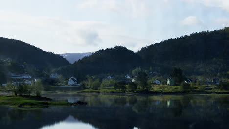 Hand-held-shot-of-waterfront-houses-reflecting-in-the-peaceful-lake-in-Vestland