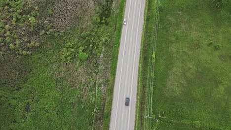 Car-Driving-On-Road-Between-Agricultural-Fields---aerial-top-down