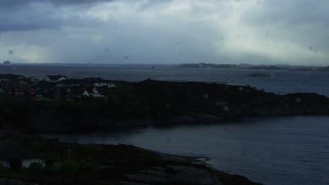 Slow-motion-dolly-shot-of-seafront-houses-under-moody-lighting-in-Norway