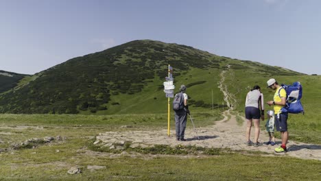 A-family-in-the-mountains-looking-for-directions-on-their-mobile-phone-at-a-fork-in-the-road