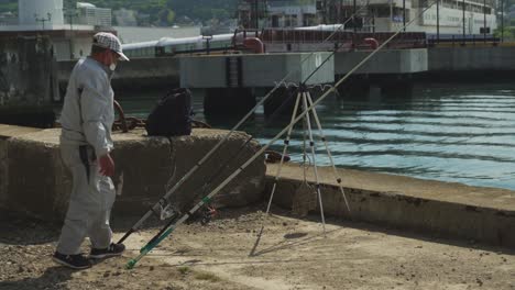 Local-Fishermen-Setting-His-Line-With-Fishing-Rod-Resting-Beside-Pier-At-Port-of-Hakodate