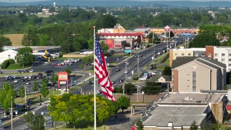 Towering-American-flag-in-center,-overlooking-busy-highway,-tanger-outlets