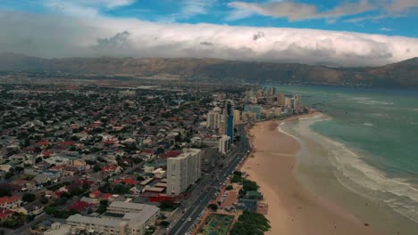 Etablierte-Luftaufnahme-Von-Kapstadt-Mit-Blick-Auf-Den-Strand,-Stadtbild-Und-Dramatisches-Wetter,-Küstenlinie-Der-Camps-Bay,-Twelve-Apostles-Mountains