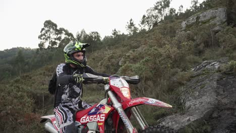 Medium-Shot-Of-Motocross-Rider-Trying-Hard-To-Climb-In-Soil-At-Beautiful-Mountain-Landscape