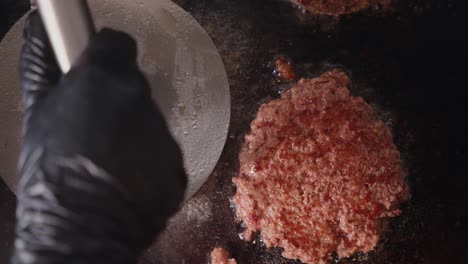 Hamburger-Essen,-Fleisch,-Gebraten,-Professioneller-Koch,-Der-Mit-Schwarzen-Handschuhen-Zubereitet,-Hände-Von-Oben-Nach-Unten,-Nahaufnahme-In-Zeitlupe
