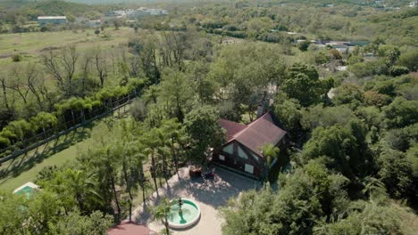 Aerial-over-picturesque-house-with-the-pool-surrounded-by-nature-and-located-near-the-river