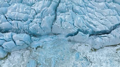 Aerial-view-tilting-in-front-of-a-large-glacier-ice-wall,-in-cloudy-Vatnajokull,-Iceland