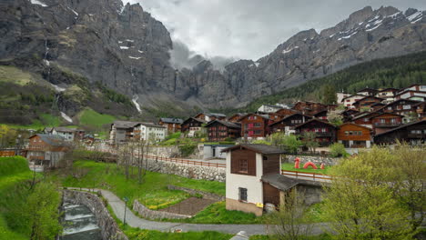 Timelapse-of-Leukerbad,-Village-in-Swiss-Alps,-Homes,-Green-Landscape-and-Steep-Cliffs