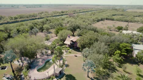 -Aerial-over-picturesque-house-with-the-pool-surrounded-by-nature-and-located-near-the-river