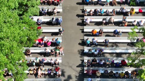 Aerial-view-of-a-community-gathering-in-a-local-park-on-bleachers-watching-a-performance-on-a-beautiful-summer-day