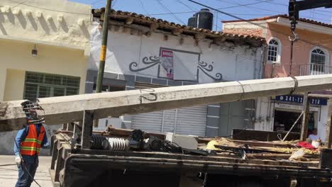 Damaged-concrete-utility-pylon-being-loaded-onto-flatbed-truck-using-crane