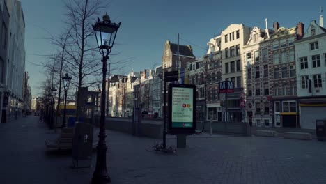 Leere-Straßen-Von-Rokin-In-Amsterdam,-Halten-Sie-Während-Der-Sperrung-Von-Covid19-Abstand-Auf-Dem-Digitalen-Werbemonitor-Am-Straßenrand,-Gimbal-Aufnahme