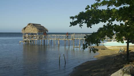 Punta-Gorda-Strand-In-Roatan,-Honduras-Tagsüber,-Wenn-Eine-Person-über-Einen-Rustikalen-Holzsteg-Zum-Strand-Geht