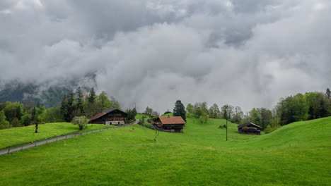 Zeitraffer,-Schweizer-Alpen-Im-Frühling,-Wolken-Ziehen-Im-Tal,-Grüne-Wiesen-Und-Häuser-An-Der-Straße