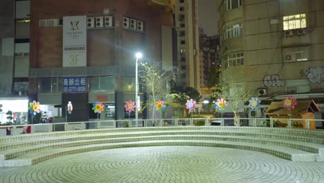 Empty-round-meeting-area-in-park-with-flower-windmills-spinning-at-night-in-asia