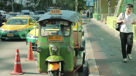 Green-Tuk-Tuk-Taxi-Driver-Waiting-Along-Sidewalk-in-Bangkok,-Thailand