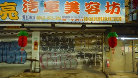 Push-in-towards-graffiti-on-metal-grate-garage-door-panels-in-front-of-shop-in-asia