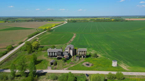 Kreisförmiger-Drohnenflug-Um-Einen-Bauernhof-Mit-Getreidesilos,-Umgeben-Von-Großen-Wiesen