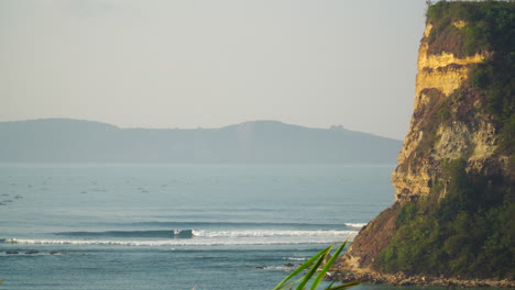 Statische-Luftaufnahme-Des-Surfspots-Gerupuk-Mit-Klippen-Und-Wellen-An-Einem-Nebligen-Tag-In-Indonesien