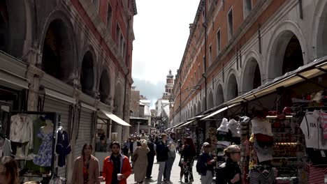 View-Looking-Along-Ruga-dei-Oresi,-2-Towards-Rialto-Bridge-With-Tourists-Walking-Past-Shops-In-Venice