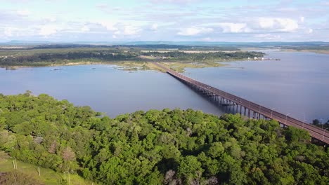 Panning-aerial-drone-shot-of-a-long-bridge-in-a-landscape-of-forests,-lakes,-rivers,-and-islands