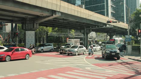 Busy-Traffic-Light-Intersection-in-Bangkok,-Thailand-with-Motorbikes