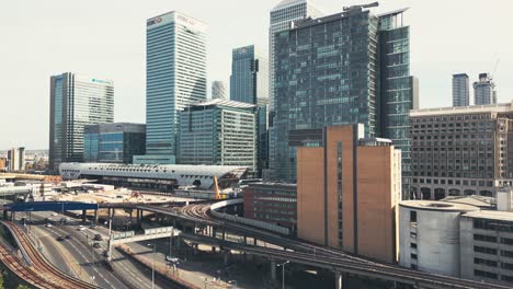 Canary-Wharf-business-complex-skyline-buildings,-Train-station-and-freeway-with-moving-traffic,-New-York