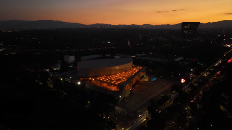 Drohnenschuss-Umkreist-Das-Nächtlich-Beleuchtete-Nationalauditorium,-Sonnenuntergang-In-Mexiko-Stadt