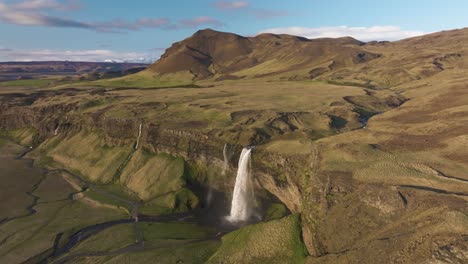 Aerial-View,-Amazing-Landscape-of-Iceland,-Waterfall,-Cliffs-and-Green-Pastures-on-Sunny-Summer-Day,-Drone-Shot