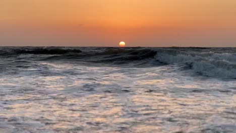 Filmische-Aufnahme-Von-Sonnenuntergang-Und-Sonnenaufgang-Am-Strand-Von-Goa,-Große-Wellen-Kommen-In-Die-Kamera-Und-Farbenfroher-Sonnenuntergang-Glüht-Am-Himmel,-Nachdem-Die-Sonne-Untergegangen-Ist
