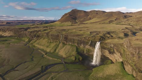 Scenic-Seljalandsfoss-waterfall-with-the-view-of-icelandic-plateau,-mountain-peak-and-valley,-Iceland,-Aerial-shot