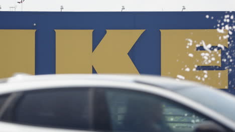 Icónico-Cartel-Amarillo-Y-Azul-De-Ikea-Detrás-De-La-Fuente-Y-El-Tráfico-De-Automóviles