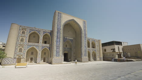 Landschaft-Einer-Person-In-Der-Ferne,-Die-Die-Madrasa-Mirzo-Ulughbeg-In-Buchara-In-Usbekistan-Betritt