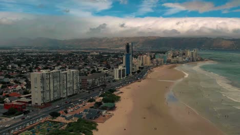 Cámara-Aérea-Moviéndose-Hacia-Atrás-De-La-Ciudad-Del-Cabo-Desde-La-Colina-De-La-Señal-Después-Del-Atardecer-Durante-La-Hora-Azul,-Ciudad-Moderna-Con-Un-Espectacular-Panorama-Nocturno,-Espectacular-Paisaje-Marino-Atmosférico