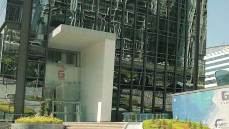 Entrada-Exterior-Del-Edificio-De-La-Torre-G-Con-Reflejos-De-Tráfico-En-La-Ventana-En-Bangkok,-Tailandia