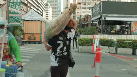 Delivery-Man-at-Jodd-Fairs-Outdoor-Market-Carrying-Product-on-Shoulder-in-Bangkok